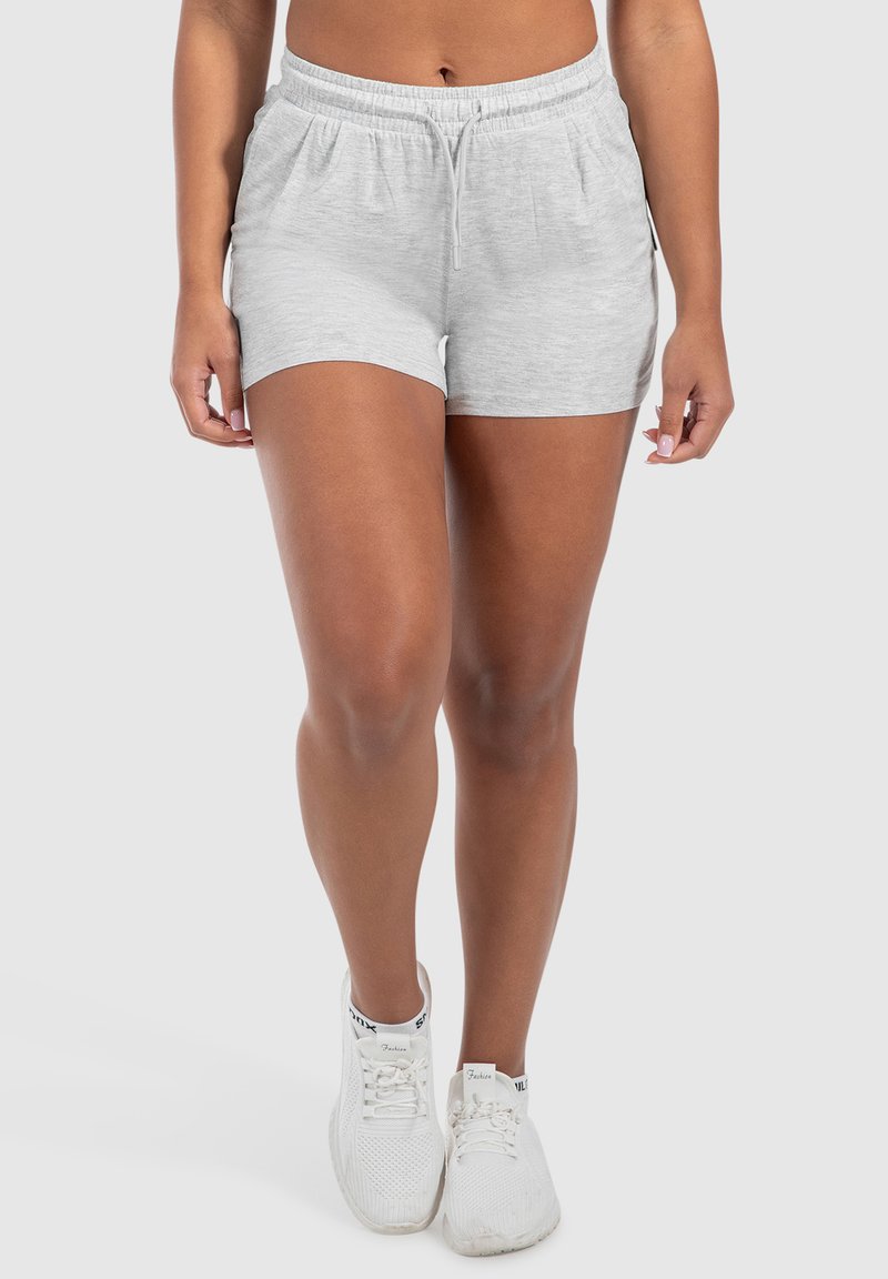 Pantaloni corti in cotone grigi con cintura elastica e cordoncino, dotati di tasche laterali e design aderente e casual. Indossati con sneakers bianche.