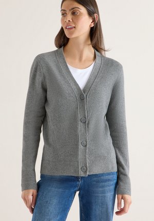 Grå cardigan med V-hals, fem knappar, ribbade ärmslut och nederkant. Mjuk textur, enkel design, i kombination med en vit skjorta och blå jeans.