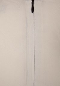 Gros plan d'une fermeture éclair en tissu beige avec le curseur centré et la fermeture éclair fermée le long de la couture verticale.