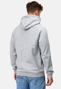 Sudadera gris con una textura suave, que presenta una capucha, puños y dobladillo acanalados, combinada con jeans de mezclilla azul claro.
