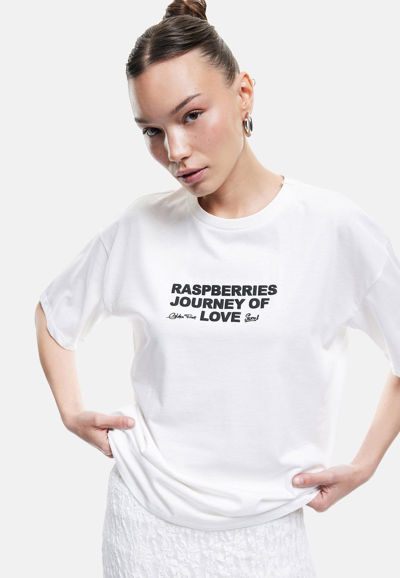 Camiseta blanca de algodón de manga corta con texto negro: "RUTA DEL AMOR DE LAS FRAMBUESAS" y un detalle de firma debajo.