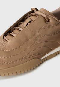 Brune semsket sneakers med riflet såle, tonale snører og søm detaljer med "BOSS"-logoet på siden.