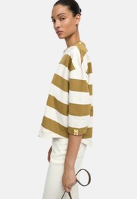 Paski, oversize t-shirt w kolorze musztardowym i białym, wykonany z bawełny, posiada okrągły dekolt, obniżone ramiona oraz małe logo na rękawie.