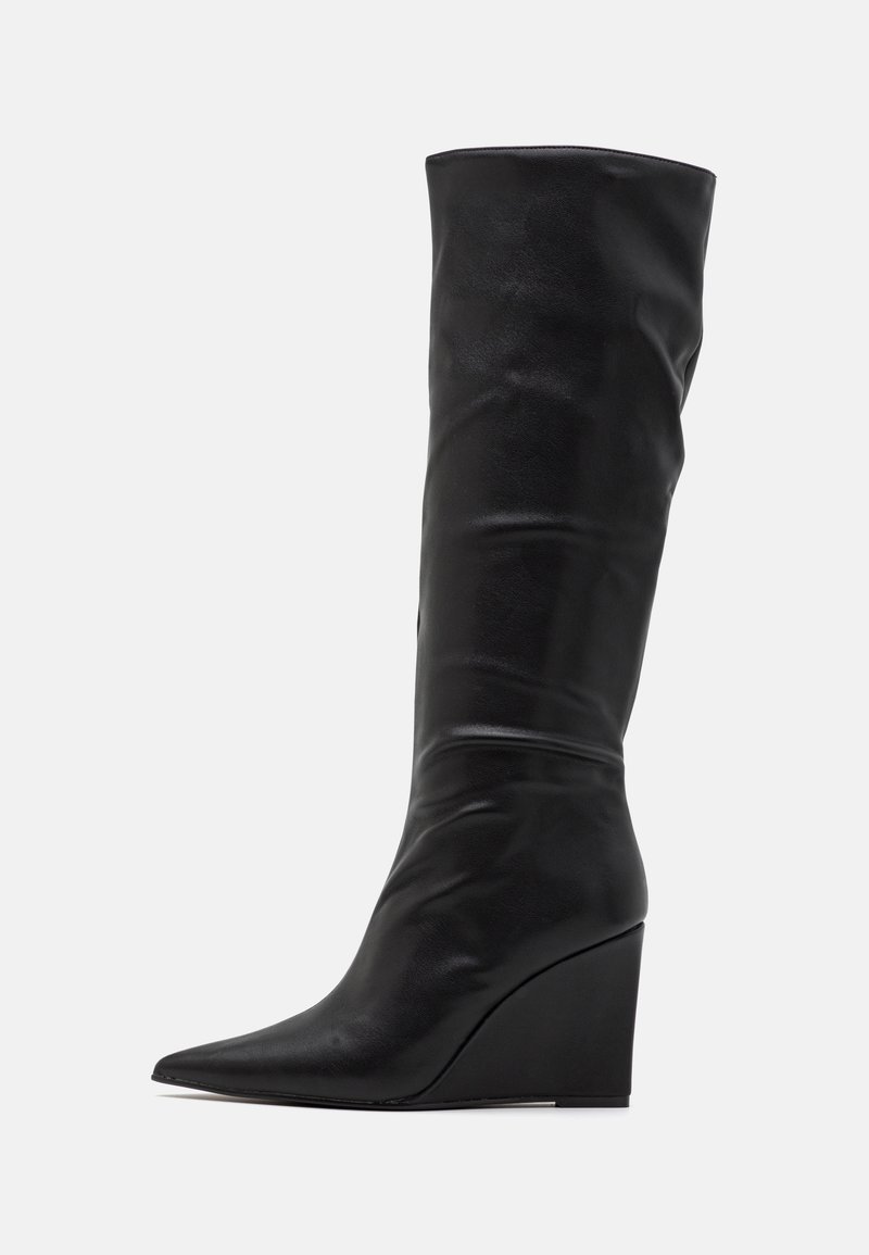 Botte noire en cuir montante jusqu'au genou avec un talon compensé, un bout pointu et une texture lisse sur un fond clair uni.