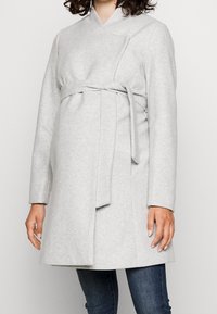 Lichtgrijze wikkeljas van zachte stof, met lange mouwen, een striksluiting in de taille en een vlak kraagontwerp.