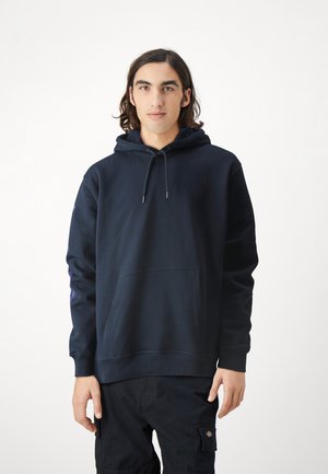 Navy blue hooded sweatshirt made of soft fabric, features a front kangaroo pocket, adjustable drawstrings, and logo detail on the sleeve.
