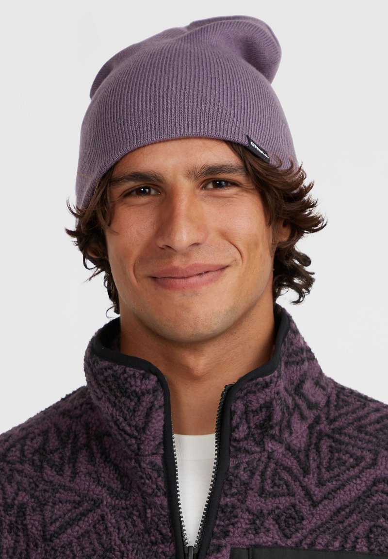 Paarse gebreide muts met een geribbelde structuur, voorzien van een slouchy bovenkant. Draagt men met een donkere paarse fleece jas met textuur.