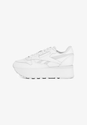 Zapatillas de cuero blancas con una suela de plataforma gruesa blanca, puntera perforada y acentos en los paneles laterales que presentan una textura suave.