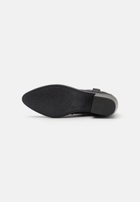 Suela de zapato negra con patrón texturizado y un ligero tacón. Presenta una superficie lisa con una punta redondeada y un diseño sólido y duradero.