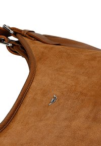 Bruine suède handtas met een gladde textuur en contrasterende leren details. Beschikt over een zilveren logo accent en verstelbare strap hardware.
