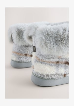 Harmaat pehmeät tohvelit, joissa on pörröinen resori ja raidallinen kuviointi kermaan, harmaaseen ja vaaleaan ruskeaan. Pohjassa näkyy sileä harmaa pohja.