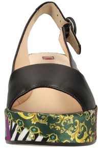 Sandale en cuir noir à bout ouvert, bride de cheville ajustable, et plateforme à motif vert, noir et violet avec des accents dorés.