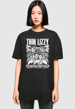 Juodas medvilnės marškinėliai su grafiniu dizainu, kuriame yra "Thin Lizzy" užrašas, drugeliai ir senovinis televizorius. Laisvas kirpimas, trumpomis rankovėmis.