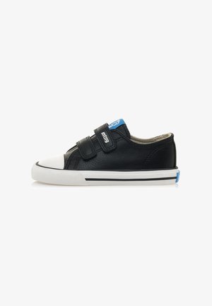 Sneaker in pelle nera con punta e suola in gomma bianca. Presenta due strap in Velcro e un accento blu sulla parte posteriore. Parte superiore testurizzata con dettagli di cucitura.