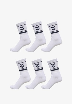 Weiße Sportsocken mit gerippten Bündchen, die navyblaue Chevronmuster und Streifen aufweisen. Sechs Paare sind leicht geneigt präsentiert.