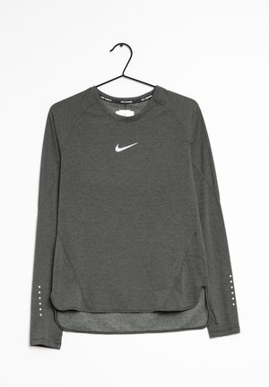 Camiseta de running de manga larga Nike de color gris oscuro con sutil textura a rayas, logo blanco en el pecho y puntos reflectantes en las mangas, colgada en una percha negra.