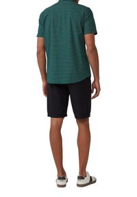 Kortemouw groen geruit shirt, gecombineerd met donkere shorts en witte sneakers, met een relaxte pasvorm en ademende stof.
