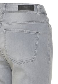 Lysegrå denimjeans set bagfra med en enkelt lomme og en sort lædermærkat med mærket "ICHI" på linningen.