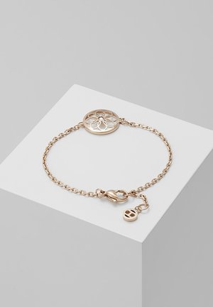 Fijn gouden schakelkettinkje met ronde hanger met bloemmotief en sluiting met karabijnhaak, tentoongesteld op een wit geometrisch voetstuk.