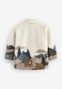 Veste polaire de couleur crème avec un design paysager montrant des montagnes, des arbres et deux ours bruns sur le bas du dos et les manches.