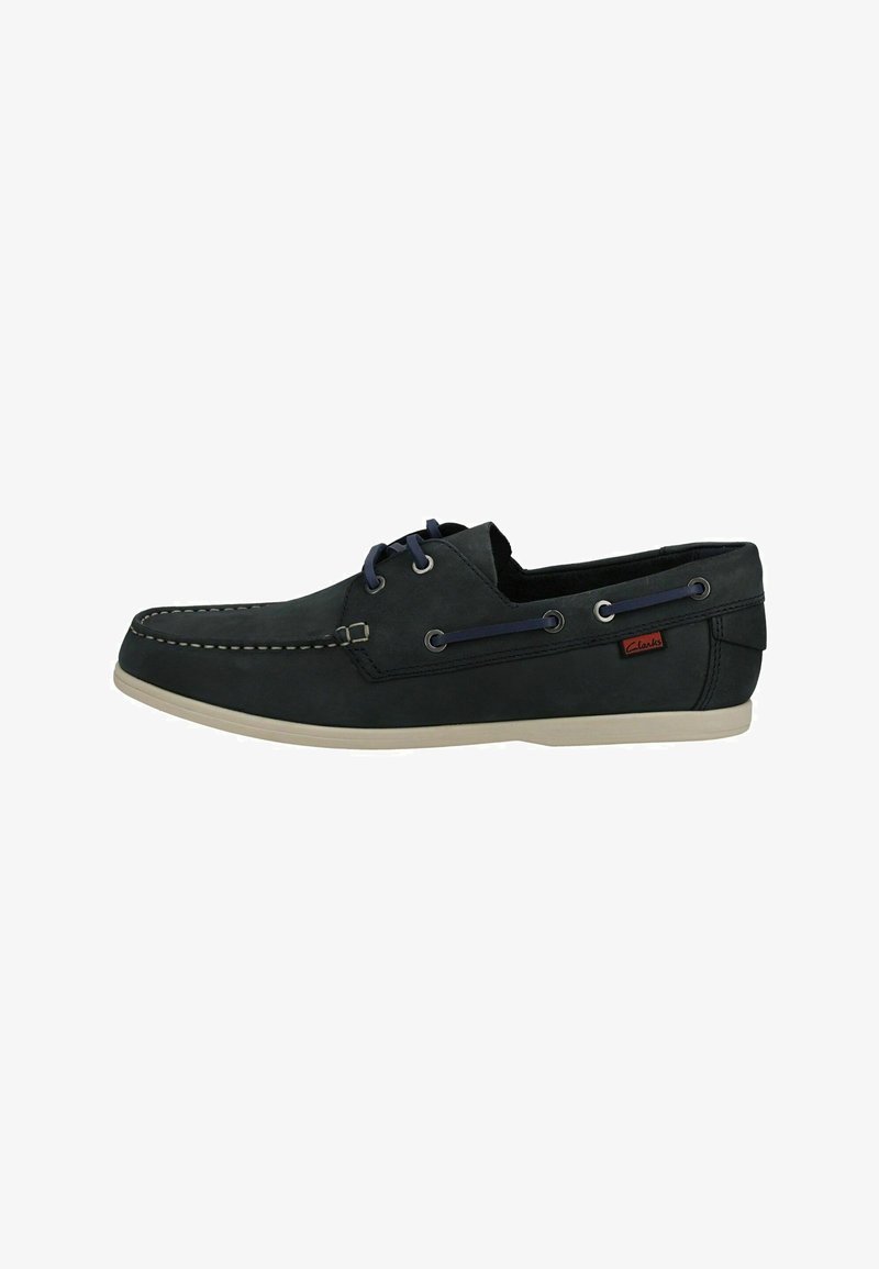 Chaussure bateau en cuir bleu marine foncé pour homme avec semelle beige, détails de laçage latéral et étiquette rouge de marque près du talon.