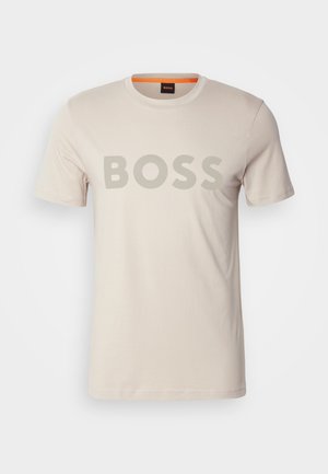 T-shirt di cotone color crema a maniche corte, con un grande logo grigio "BOSS" sul petto e un accento arancione sul collo.