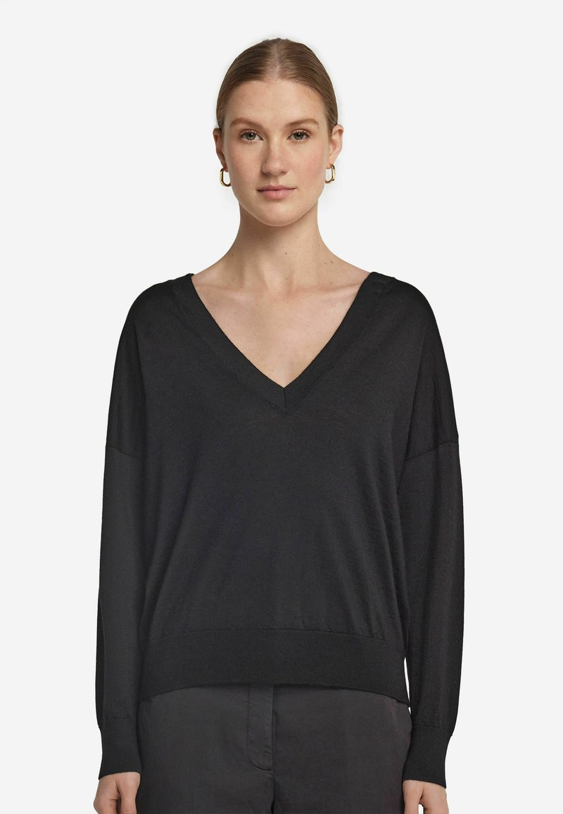 Svart långärmad tröja med V-ringning, tillverkad av mjukt tyg. Har avslappnad passform och ribbad nederkant. Enkel, minimalistisk stil.