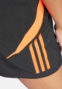Schwarze Sportshorts mit einem orangen Seitenpanel und drei vertikalen Streifen, aus leichtem, feuchtigkeitsableitendem Material hergestellt.