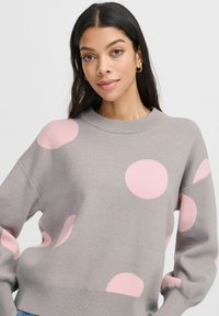 Light grey sweater with large pink polka dots. Features a crew neckline and relaxed fit, made from soft, textured fabric.