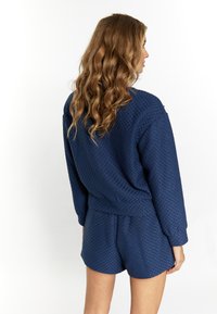 Navyblauwe getextureerde gebreide loungewearset met lange mouwen en shorts. Heeft een relaxte pasvorm en een elastische tailleband.