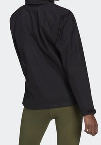 Svart vattentät jacka med hög krage, långa ärmar och justerbara ärmslut. Mjuk textur och minimalistisk design, lämplig för lager på lager.