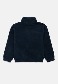Pile blu navy con collo alto, caratterizzato da una superficie morbida e strutturata, vestibilità rilassata, maniche lunghe e orlo dritto.