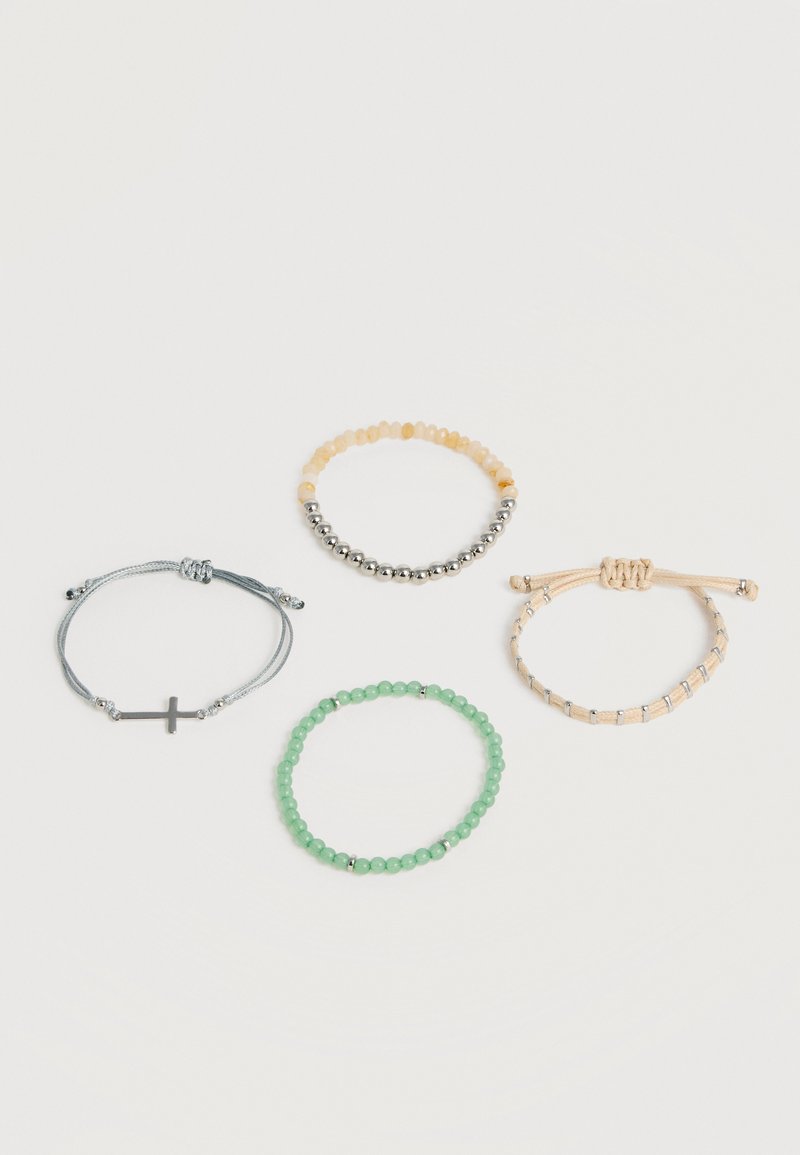 Τέσσερα βραχιόλια σε λευκή επιφάνεια: ένα γκρι με σταυρό, ένα με μικτούς κίτρινους και ασημένιους χάντρες, ένα μπεζ με ασημένιες λεπτομέρειες και ένα με πράσινες χάντρες.