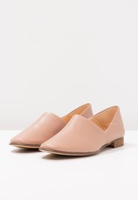 Des chaussures en cuir rose à enfiler avec un design à bout pointu et un petit talon en bois. Texture lisse avec un minimum de détails et une silhouette épurée.