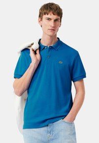 Polo shirt blu in cotone, con colletto classico, pattina con due bottoni, maniche corte e un piccolo logo verde sul petto.