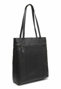 Zwarte leren tote bag met twee lange handvatten en een voorvak met rits, rechtopstaand op een witte achtergrond.