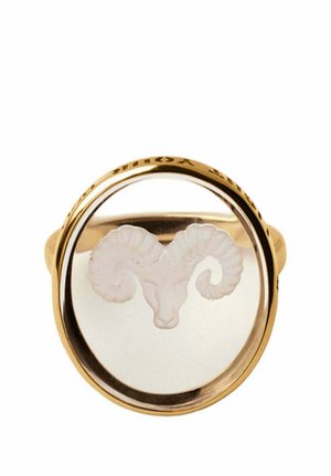 Anillo de oro con una cara redonda clara que presenta una cabeza de carnero blanca grabada con cuernos curvados en el centro.