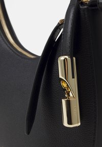 Borsa a tracolla in pelle nera con una superficie liscia, dettagli in metallo dorato e un originale sistema di chiusura. Apertura con zip nella parte superiore.