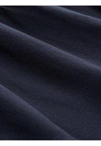 Tissu bleu marine foncé avec une texture lisse, présentant de subtils motifs côtelés et des plis délicats, mettant en valeur sa flexibilité et sa douceur.