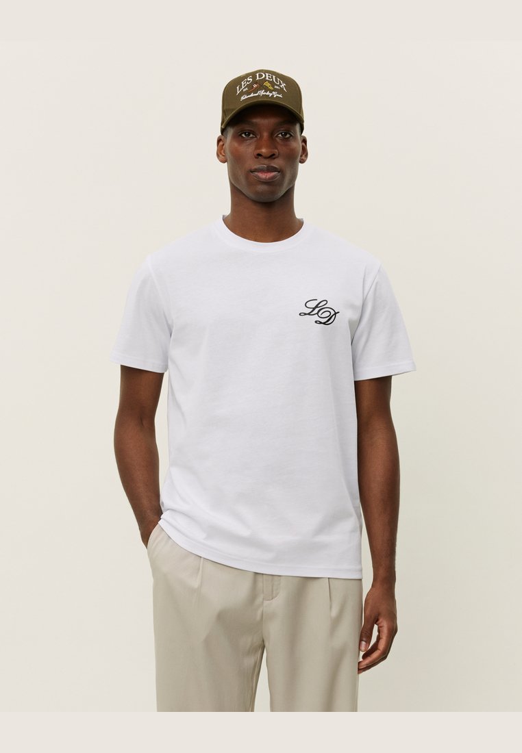 Camiseta de algodón blanca de manga corta y escote redondo, con un pequeño logotipo bordado en negro "LD" en el lado izquierdo del pecho.
