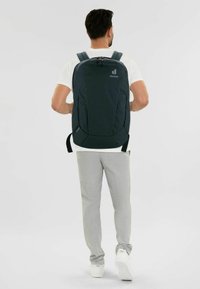 Dunkelgrüner Rucksack mit gepolsterten Trägern, einem strukturierten Design und einem Logo. Glattes Gewebe mit Reißverschlüssen und funktionalen Seitentaschen.