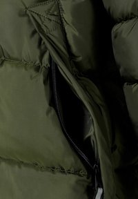 Giacca puffa verde oliva con una tasca zip visibile, caratterizzata da un tessuto liscio e lucido e una trama trapuntata.