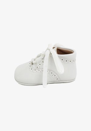 Zapato de bebé blanco con cierre de cordones, perforaciones decorativas, suela blanda y material de cuero suave.