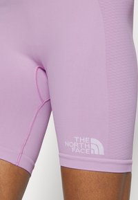 Fialové sportovní šortky s přiléhavým střihem, hladkou texturou a detailem loga značky The North Face na lemu.