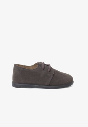 Šedá semišová bota s kulatou špičkou, plochou gumovou podrážkou a hnědými tkaničkami. Má minimální prošívání a jednoduchý, čistý design.