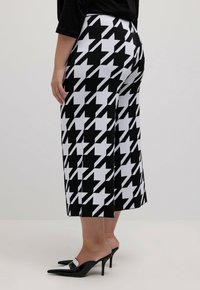 Zwart-wit geblokte culottes van structuurstof, met een wijde pijp en een hoge taille. Draag ze met puntige hakken.