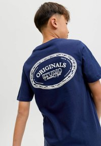 Marineblauwe katoenen T-shirt met een grote witte grafische afbeelding op de achterkant met de tekst "ORIGINALS STUDIO Creative Dept." en een decoratieve rand.
