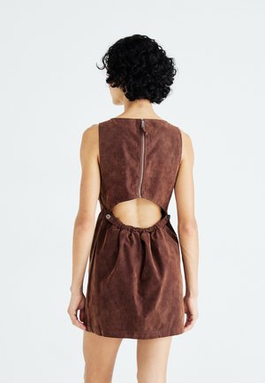 Brown suede dress featuring a high neckline, back zipper closure, and an open back with drawstring detail at the waist. Smooth texture.