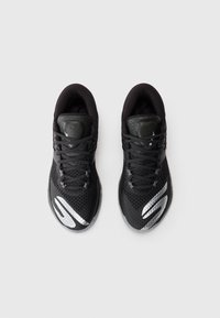 Baskets de sport noires avec une tige en mesh texturé, des accents réfléchissants et une languette rembourrée. Les lacets sont gris foncé et présentent un design de soutien.