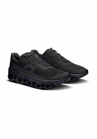 Czarne buty sportowe z oddychającą siateczką u góry, wzmocnionym noskiem i unikalną, amortyzującą podeszwą z pustymi wycięciami.